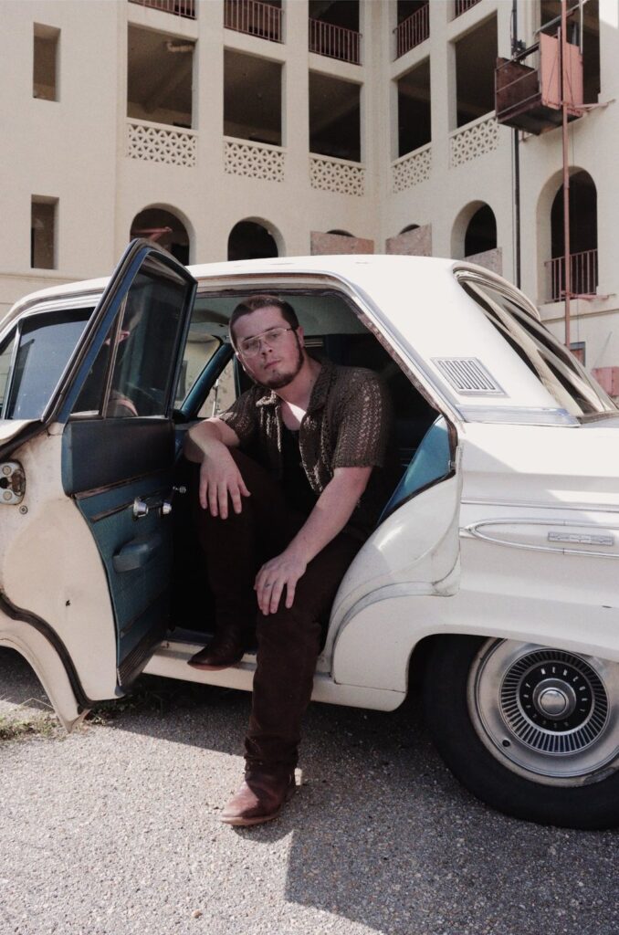 Tyler Nichols sitting in the open door of a vintage car